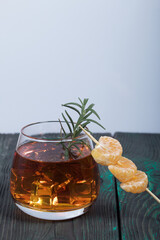 Alcoholic cocktail. Garnished with rosemary slices and tangerine wedges. Close-up shot.