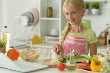 Obraz na płótnie Canvas cute girl making salad on kitchen