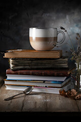 Latte coffee and stack of books on wooden table