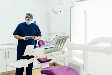 Dentist consults online information with a tablet. Doctor reviews information about a patient in the hospital clinic.