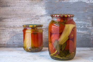 Jars of canned vegetables on a wooden background against a gray wall. Homemade vegetables for the winter
