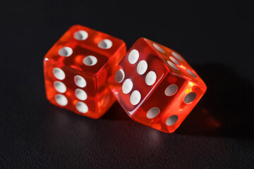 Two red glass dice on a dark leather background. The result is four and six or five. Two red dice on a dark textured background, macro photography.