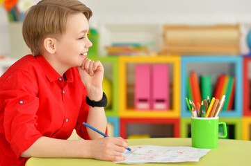 Portrait of cute little boy drawing with pencils