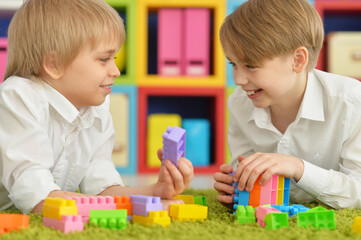 Obraz na płótnie Canvas Two boys playing with colorful plastic blocks on floor
