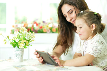 happy mother and daughter using tablet together at home