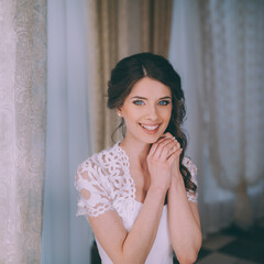 A young brunette bride poses for the camera. An emotional smiling bride.