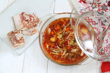 Borsch with bacon, black bread on a white wooden background