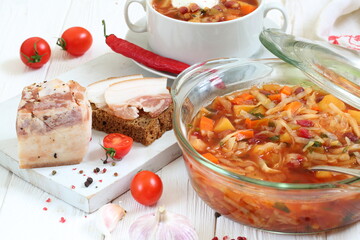 Borsch with bacon, black bread on a white wooden background