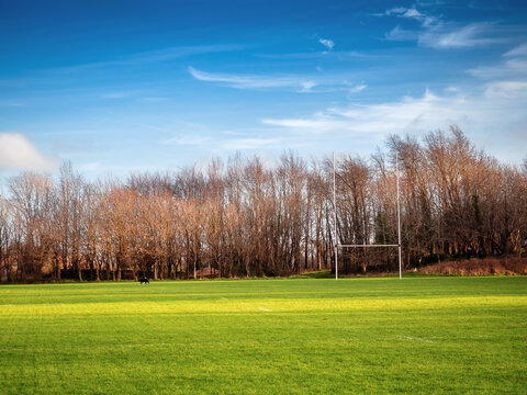 Training Ground For Irish National Sports With Tall Goal Posts. Blue Cloudy Sky, Hurling, Camogie, Rugby And Gaelic Football Pitch With Green Grass,