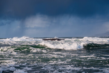 View on Atlantic ocean. Mullaghmore peninsula county Sligo. Powerful waves rolling in the ocean. Cloudy sky. Rough stone coast line. Warm sunny day