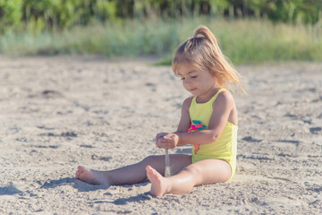 Little adorable girl sitting on the sand at the beach.