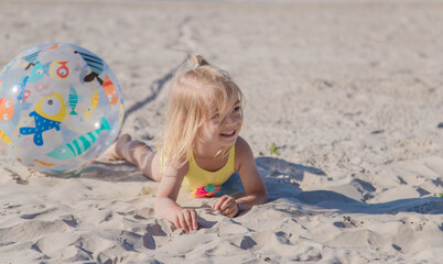 Little girl have fun on the beach with beachball. Active game on the beach.