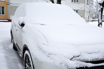 car covered with snow in the winter blizzard in the parking lot