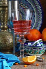 Oriental still life with red wine and oranges on wooden background