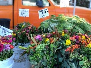 flowers for sale at farmers market in spring with orange truck in background 