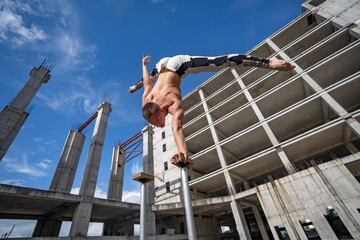 Flexible male circus Artist keep balance on one hand against amazing cloudscape and modern constructions . Individuality, creativity and modern point of view concept