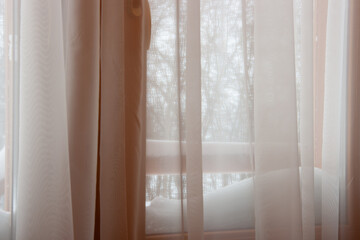 Curtains on the window against a background of snow