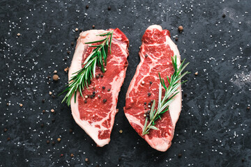 Raw New York striploin beef steak isolated on black background with sea salt and rosemary and...