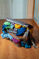 Suitcases overflowing with used clothes on the floor. Sorting wardrobe and textiles. Sustainable life