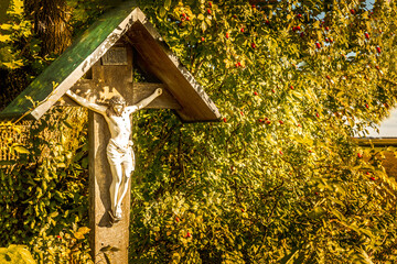 Wayside cross with in Bavaria next to a tree in autumn
