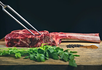 Dry aged wagyu tomahawk steak on a wooden cutting board with spices and parsley