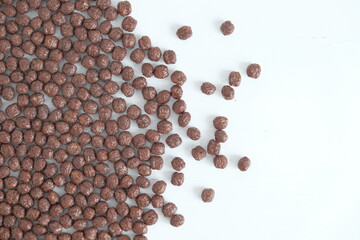 Chocolate corn balls scattered on a white background. Top view. Copy, empty space for text