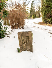 alter Feldstein  auf dem Friedhof inmitten von Schnee