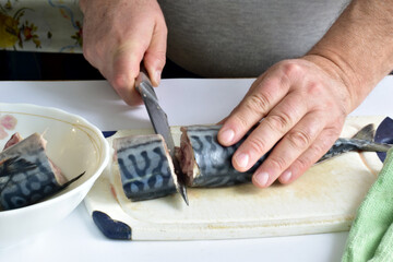 Close-up shot of male hands chopping mackerel fish.