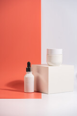 Cosmetic cream and serum or essential oil bottle on white and pink background. Bright shadows. Beauty product concept.