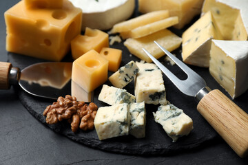 Composition with different sorts of cheese and knives on black table, closeup