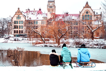 three children sit on a sled against the background of an old building in winter in poland in wroclaw