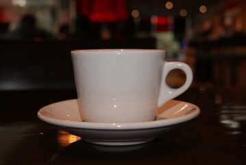 tasa de café blanca sobre mesa de madera con fondo desenfocado