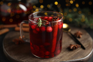 Tasty hot cranberry tea with rosemary and cinnamon on wooden table, closeup