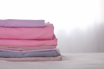 Stack of clean color folded linens on bed. Space for text