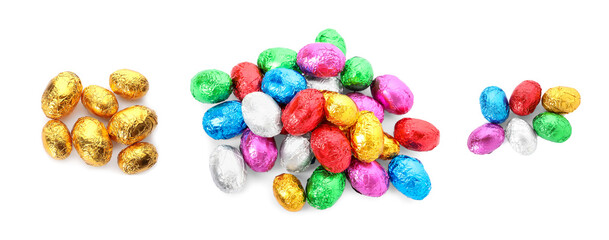 Fototapeta na wymiar Set with chocolate eggs wrapped in bright foil on white background, top view. Banner design