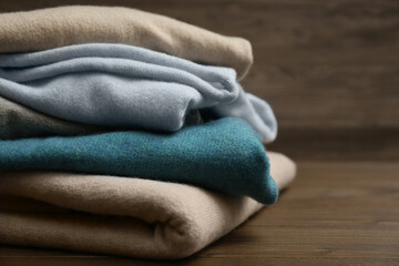 Stack of cashmere clothes on wooden background, closeup