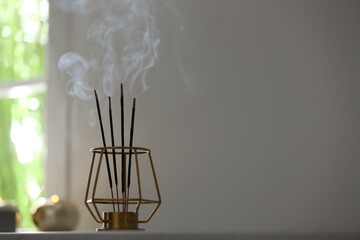 Incense sticks smoldering on table in room. Space for text