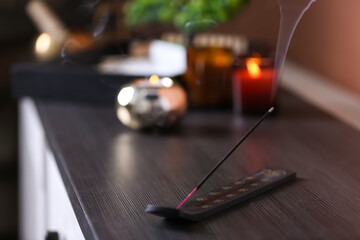 Obraz premium Incense stick smoldering on wooden chest of drawers in room. Space for text