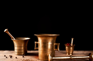 iron mortar and pestle on a wooden table with black pepper