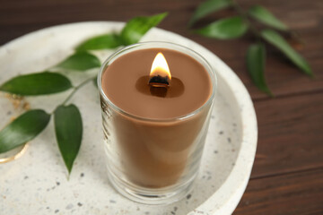 Burning candle with wooden wick on tray