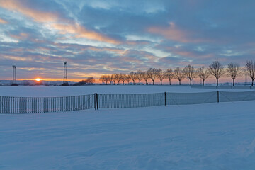 landscape with snow fence in sunset 