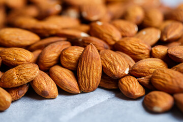 Delicious roasted sweet almonds lie in a large heap, nuts close-up.