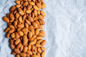 Delicious roasted sweet almonds lie in a large heap, nuts close-up.