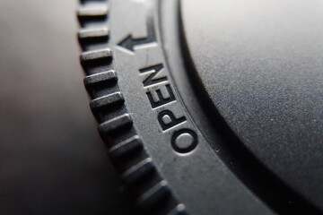 Macro photo of camera lens cap with word OPEN on it.