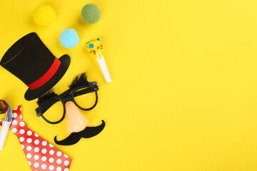 Flat lay composition with clown mask and tie on yellow background. Space for text