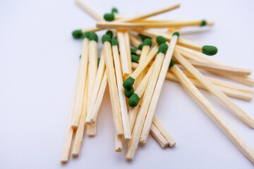 Small pile of wooden matches with green heads on a white background. Selective focus