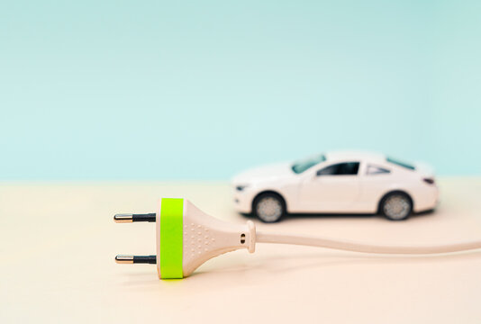 Toy Car And Electrical Plug. Electric Car And Green Car Concept . Concepts About The Growing Market For Electric Or Hybrid Cars, Online Shopping Or Replacement Of Gasoline And Diesel Engines.