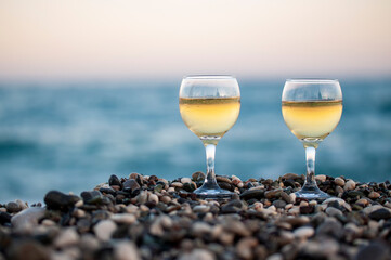 two glasses of white wine on the beach before sunset