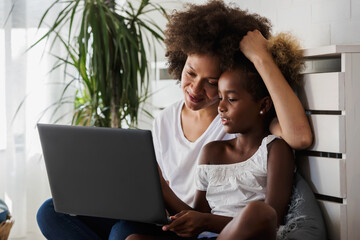 African American family. Mother and daughter using laptop computer at home or learning