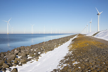 Row offshore windturbines along Ductch coast in winter with snow